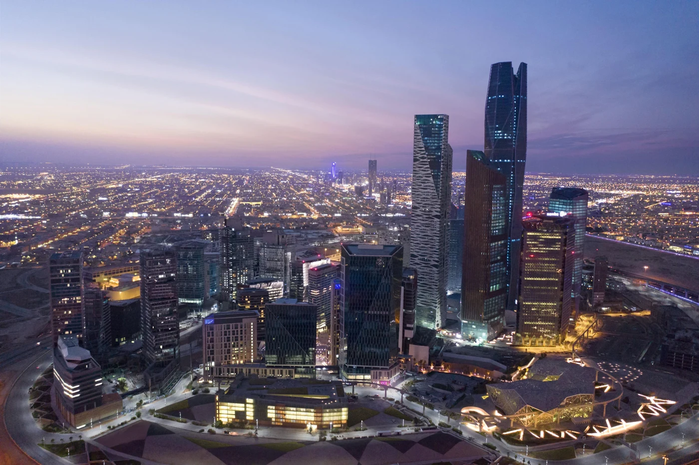An urban financial district with illuminated towers and streets at dusk